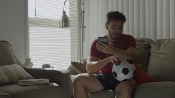 Slow motion of soccer fan kissing a soccer ball and holding mobile phone - Filmagem, Vídeo