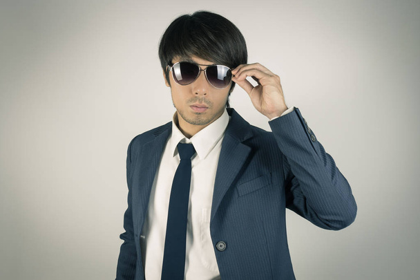 Молодой азиатский портрет Бизнесмен коснулся солнцезащитных очков в Front View
  - Фото, изображение