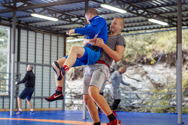 Altai, Rusland augustus 16, 2019: twee jonge mannen in worstelen panty's zijn worstel LNG en het maken van een suplex worstelen op een blauwe worstelen tapijt in de sportschool. Open training en zomer sportkampen  - Foto, afbeelding