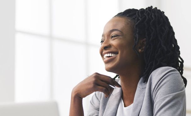 Portret van zwarte Office meisje lachen zittend tegen venster - Foto, afbeelding