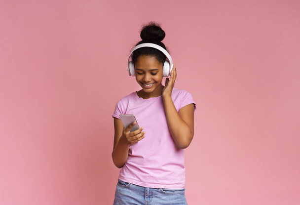 Joyful girl enjoying music with mobile app and wireless headphones - Foto, Imagen