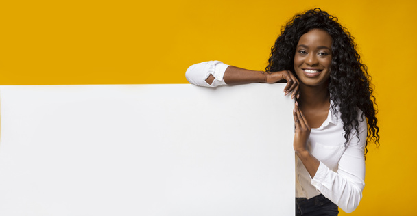 Χαμογελαστή μαύρη κοπέλα στέκεται δίπλα στην κίτρινη σανίδα - Φωτογραφία, εικόνα