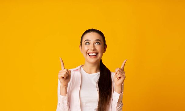 Joyful Woman Pointing Fingers Up At Copy Space, Yellow Background - Fotoğraf, Görsel