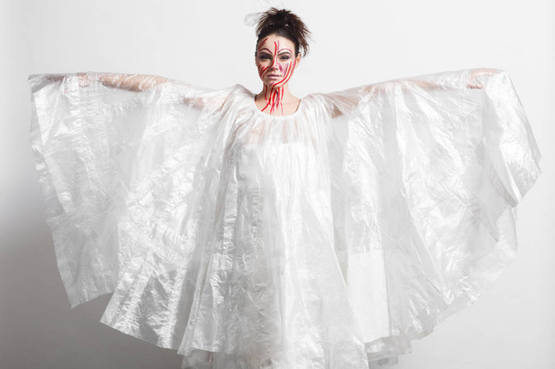 Model in a raincoat made of cellophane and in creative make-up - Foto, Imagen