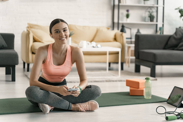Jolly sporty girl relaxing with gadgets indoors stock photo - Foto, afbeelding