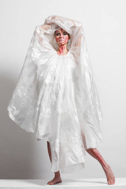 Modell im Regenmantel aus Zellophan und in kreativem Make-up - Foto, Bild
