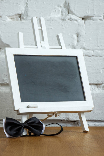 Κοντινό πλαίσιο μιας μικροσκοπίδας με κιμωλία και παπιγιόν σε ένα φόντο τοίχου με λευκό τούβλο, επιλεκτική εστίαση - Φωτογραφία, εικόνα