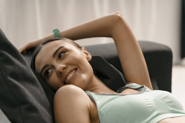 Delighted fit girl relaxing on sofa stock photo - Foto, imagen