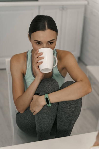 Sporty woman sipping hot beverage at home stock photo - Photo, Image