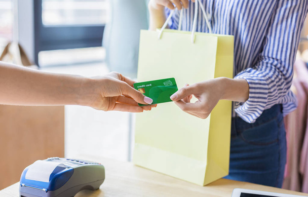 Mujer pagando con tarjeta de crédito para la compra en la sala de exposición de ropa
 - Foto, imagen