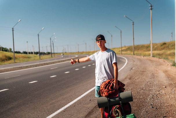 Travel man hitchhiking. Backpacker on road - Fotó, kép