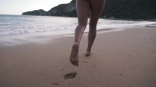 Meisje voeten en benen lopen op water golven slanke vrouwelijke benen bewegen op zee splash van water vakantie op het strand in slow motion perfecte vrouw benen vreugdevol lopen op de kust genieten van zomer vakantie. - Video