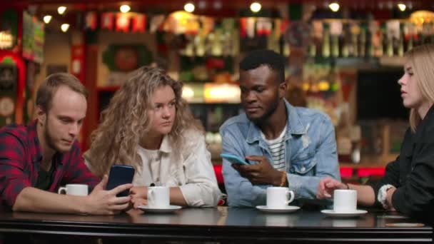 Multi-etnikai párok ülnek egy kávézóban show fotókat egymásnak, és nevetni. - Felvétel, videó
