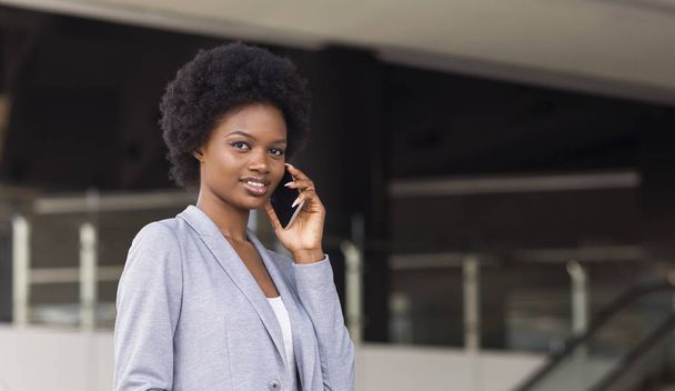 Młoda Afrykańska kobieta rozmawia na telefon przed centrum biznesowym - Zdjęcie, obraz