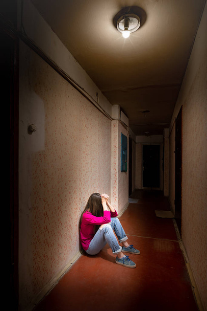 Une femme triste et désespérée est assise dans un couloir sombre
 - Photo, image