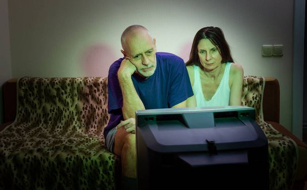 Un par de amantes adultos, sentados en un sofá ver una película en la tele
 - Foto, Imagen