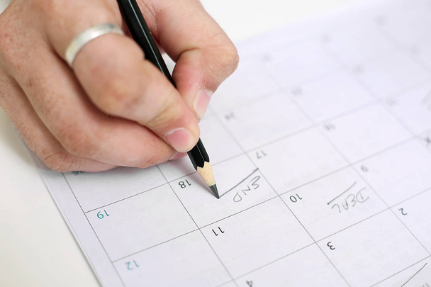 Zdjęcie człowieka trzymające kalendarz i oznakowanie w dniu. Izolowane na białym tle. - Zdjęcie, obraz