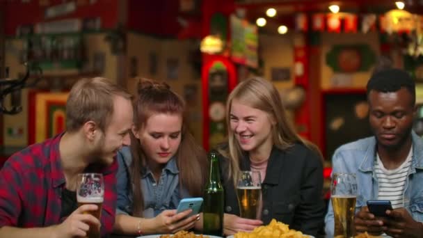 Egy férfi és két lány ül egy bárban, és nézi a telefon képernyőjén, míg a cég a barátok - Felvétel, videó