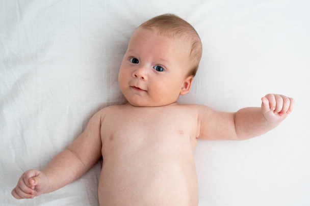 Happy baby lying on a white blanket. The concept of purity and j - Foto, imagen