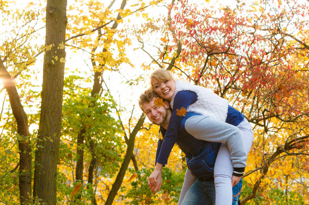 Man giving piggyback ride to woman in park - Fotografie, Obrázek