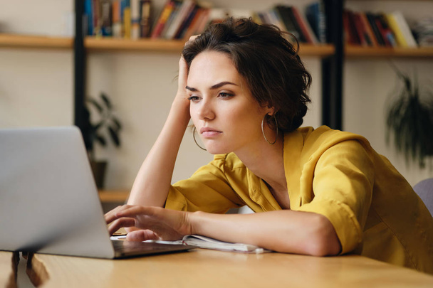 Młody zdenerwowany kobieta siedzi na biurku zmęczony pracuje nad nowym projektem z laptopem w nowoczesnym biurze - Zdjęcie, obraz