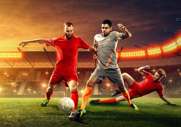 Трое футболистов дерутся за мяч во время игры на профессиональном стадионе с болельщиками
 - Фото, изображение