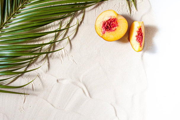 Beach vacation. A palm leaf, starfish, and white tree branch and juicy fruits lie on white fine sand. Desktop wallpaper. - Fotografie, Obrázek