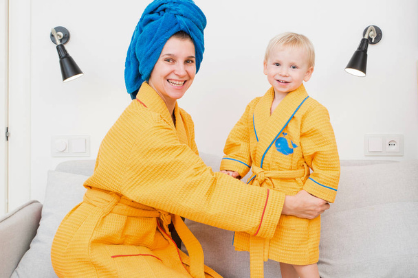Young mom and son laughing on the couch after taking a bath - Valokuva, kuva