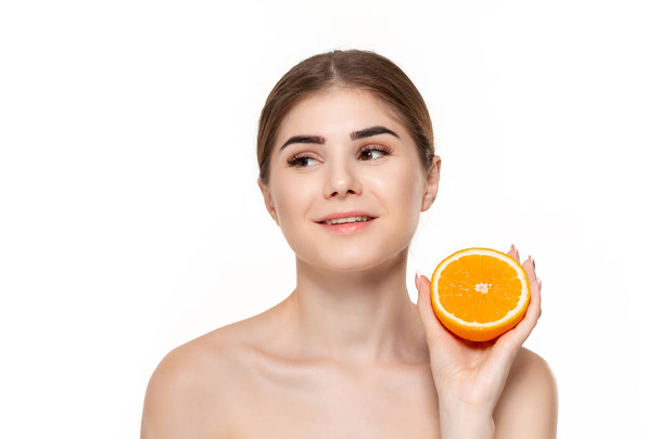 Close-up portrait of a happy beautiful young girl holding half of oranges close to face isolated over white background. - Foto, imagen