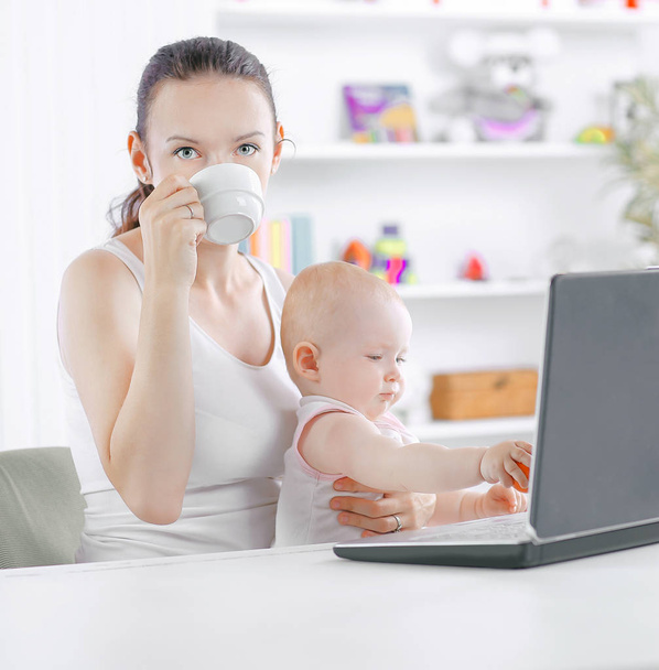 young mom with little baby sitting at the Desk.the concept of freelancing - Valokuva, kuva