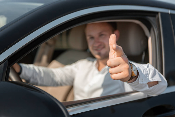 Portret szczęśliwego kierowcy w białej koszulce napędza jego luxary samochód. - Zdjęcie, obraz