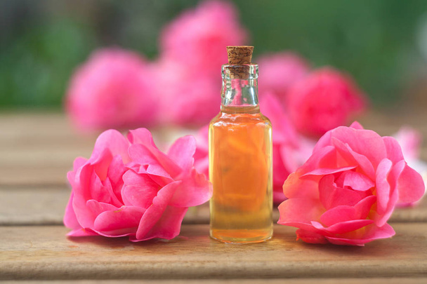 Esence z růže na stole v krásné skleněné lahvičce - Fotografie, Obrázek