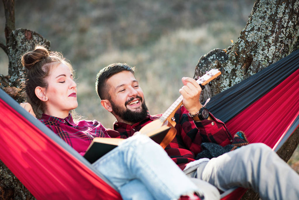 Pareja divirtiéndose en una hamaca en un picnic
 - Foto, Imagen