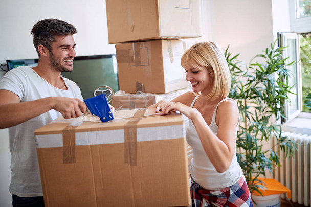 Smiling man packing box. Moving in new house. Happy famil - 写真・画像