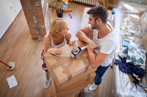 Happy woman packing box with man. Moving in new house. - 写真・画像