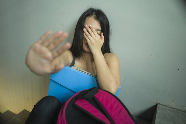 Νέος όμορφος/η λυπημένος Ασιάτης/ισσα κινέζικο φοιτητής κολλέγιο κάθεται στο Πανεπιστήμιο σκάλα θύμα της κακοποίησης νιώθοντας φοβισμένος και μοναχικά να παρενοχλούνται και να εκφοβίζονται - Φωτογραφία, εικόνα