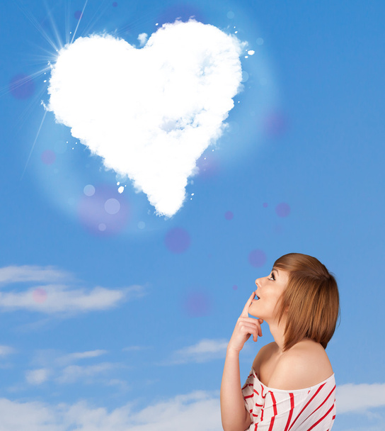 Cute girl looking at white heart cloud on blue sky - Zdjęcie, obraz