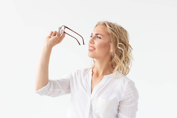 Retrato de mulher bonita concentrada com má visão tocando óculos isolados no fundo branco
 - Foto, Imagem
