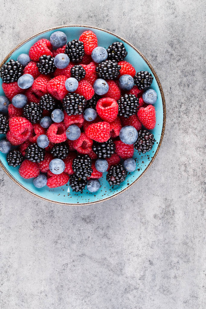 Fresh berry salad on blue dishes. Vintage wooden background. - Foto, immagini