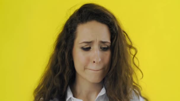 Upset young brunette woman portrait on yellow background. Young girl disappointed - Footage, Video