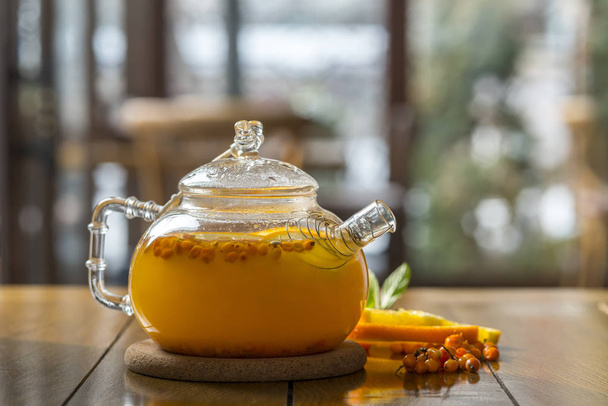 sea-buckthorn tea in a teapot on a wooden table - Foto, imagen