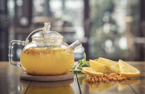 sea-buckthorn tea in a teapot on a wooden table - Φωτογραφία, εικόνα