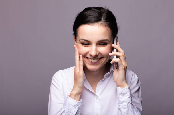menina em uma camisa branca se comunica no telefone
 - Foto, Imagem