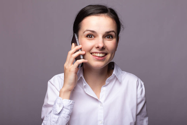 girl in a white shirt communicates on the phone - Фото, изображение