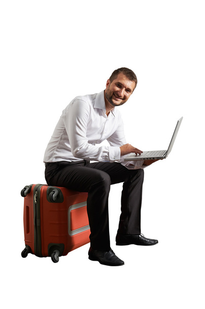 hombre sentado en la maleta y trabajando
 - Foto, Imagen