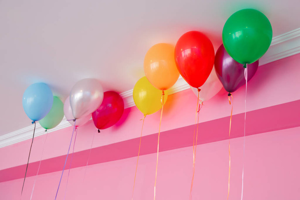 Des ballons colorés flottent sur le plafond blanc dans la pièce pour la fête. Décoration de mariage ou fête d'anniversaire d'enfants intérieur. Ballons d'hélium
 . - Photo, image