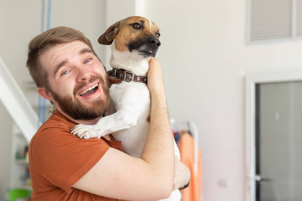 Animal, pet and people concept - Attractive cheerful man in plaid shirt holds favourite pet - Foto, imagen