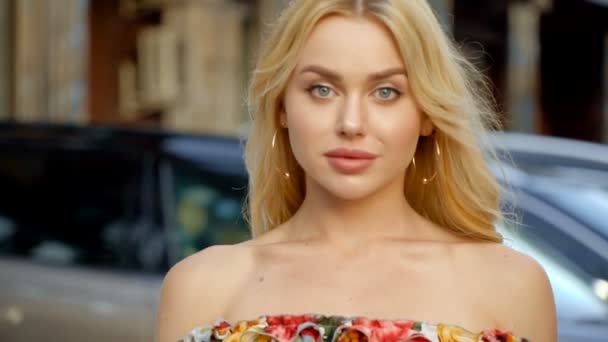 Portrét blondýny s plnými rty a modrýma očima na pozadí parkoviště - Záběry, video