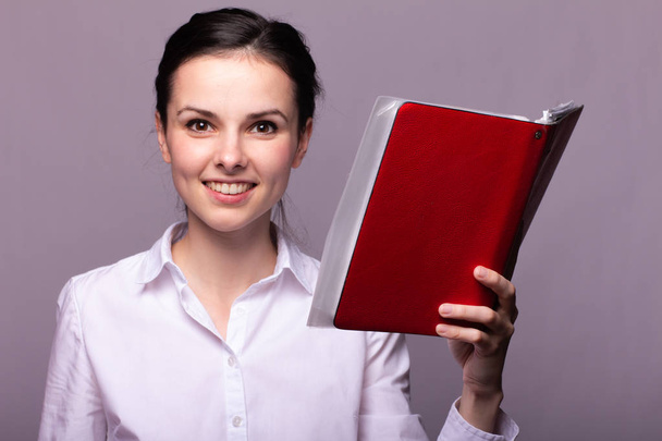 beautiful girl in a white shirt holds a notebook in her hands - Foto, Imagen