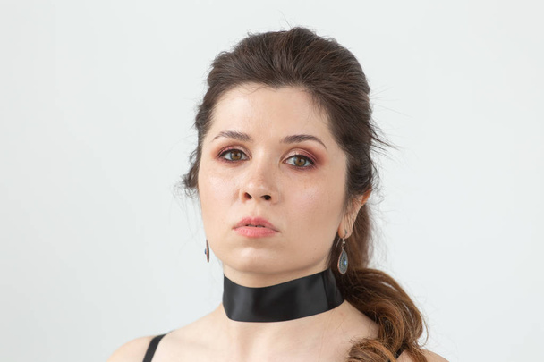 Close-up portrait of a charming pensive young beautiful woman in black clothes with a black ribbon around her neck. - Foto, afbeelding